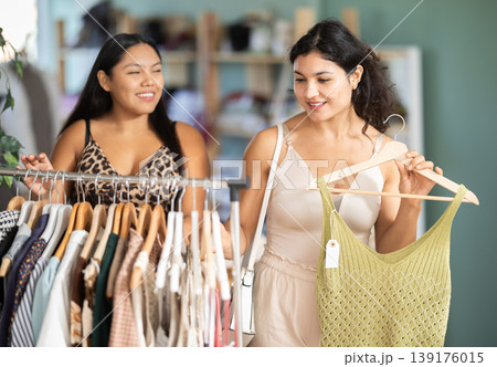 Two young women choosing summer dresses or tops in clothing store 139176015