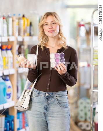 Girl housewife in household store examines goods, chooses candle 139176138
