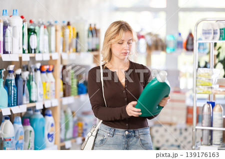 Young girl looking for household detergents on shelves in store Young girl looking for household detergents on shelves in store 139176163