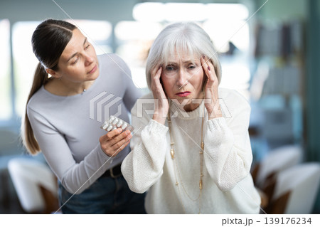 Adult woman sympathizes to sick senior female manager with headache and offers pain pills. 139176234