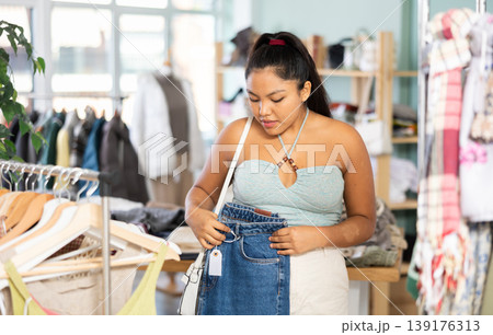 Latina chooses jeans in a clothing store 139176313