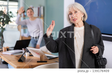 Elderly woman leaving office saying goodbye to colleague Elderly woman leaving office saying goodbye to colleague 139176409