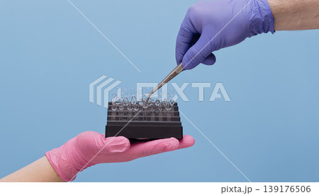Dentist hand with tweezers taking a transparent celluloid crown matrix for aesthetic tooth restoration. 139176506