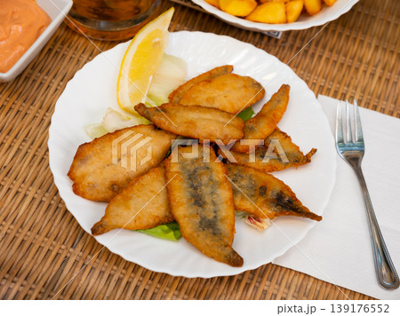 Pan-fried battered served on plate with vegetables and lemon 139176552