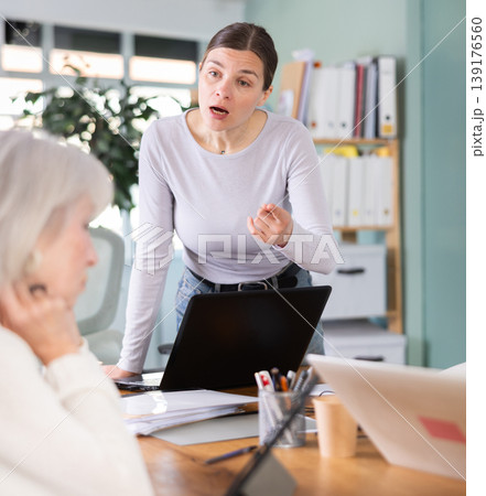 Adult woman scolding female colleague working on tablet 139176560