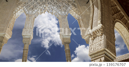Arches in Islamic (Moorish) style (against the background of a beautiful sky with clouds) in Alhambra, Granada, Spain Arches in Islamic (Moorish) style (against the background of a beautiful sky with clouds) in Alhambra, Granada, Spain 139176707