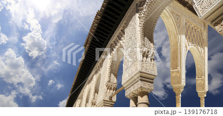 Arches in Islamic (Moorish) style (against the background of a beautiful sky with clouds) in Alhambra, Granada, Spain Arches in Islamic (Moorish) style (against the background of a beautiful sky with clouds) in Alhambra, Granada, Spain 139176718