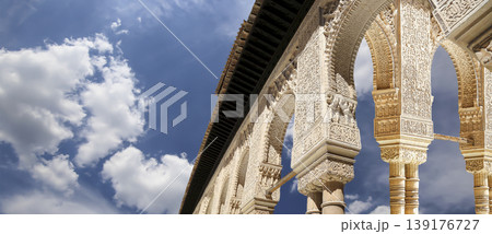 Arches in Islamic (Moorish) style (against the background of a beautiful sky with clouds) in Alhambra, Granada, Spain Arches in Islamic (Moorish) style (against the background of a beautiful sky with clouds) in Alhambra, Granada, Spain 139176727