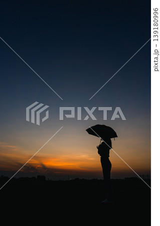 雨上がりに夕日を見つめる女性 139180996
