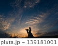 夕暮れの空を見上げる花束を持った女性 139181001