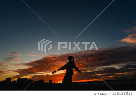 夕暮れの空を背景に嬉しさを表現する女性のシルエット 139181015