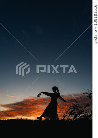 夕焼けの中、空を見上げる女性 139181016