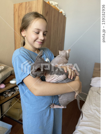Happy child with cat pet indoors. Girl 10 years old and hairless kitten 139182936