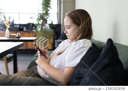 Pretty preteen child holding mobile cell phone. Girl playing games Pretty preteen child holding mobile cell phone. Girl playing games 139182939