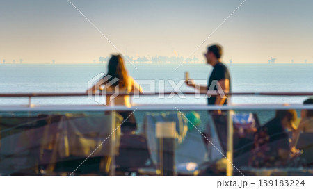 Manama, Bahrain- Jan 09 2024, Panoramic view of people walking on the upper deck of the MSC Virtuosa cruise ship, in the background the sea with oil rigs, at sunset Manama, Bahrain Manama, Bahrain- Jan 09 2024, Panoramic view of people walking on the upper deck of the MSC Virtuosa cruise ship, in the background the sea with oil rigs, at sunset Manama, Bahrain 139183224