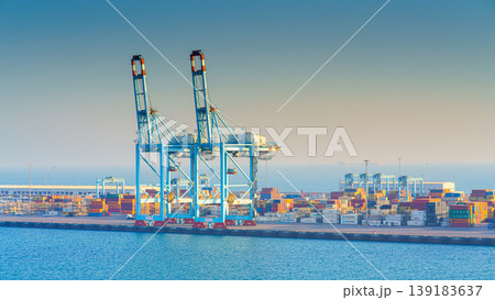 Manama, Bahrain - Jan 08 2024, Panoramic view of Bahrain commercial port with blue cranes, buildings and containers, with sea on foreground, by the morning, dawn, sunrise, Manama, Bahrain Manama, Bahrain - Jan 08 2024, Panoramic view of Bahrain commercial port with blue cranes, buildings and containers, with sea on foreground, by the morning, dawn, sunrise, Manama, Bahrain 139183637