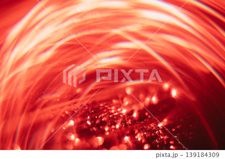 Abstract red light patterns with swirling shapes and reflections creating a dynamic visual effect, illuminated background with glimmering particles visible Abstract red light patterns with swirling shapes and reflections creating a dynamic visual effect, illuminated background with glimmering particles visible 139184309