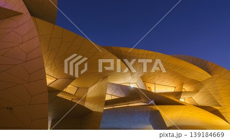 Doha, Qatar - Jan 06 2024, a bottom up view of National Museum of Qatar part of facade, exterior, in courtyard, patio shaped like a desert rose, at nighttime, with illumination, Doha, Qatar  139184669