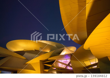 Doha, Qatar - Jan 06 2024, a bottom up view of National Museum of Qatar part of facade, exterior, in courtyard, patio shaped like a desert rose, at nighttime, with illumination, Doha, Qatar Doha, Qatar - Jan 06 2024, a bottom up view of National Museum of Qatar part of facade, exterior, in courtyard, patio shaped like a desert rose, at nighttime, with illumination, Doha, Qatar 139184812