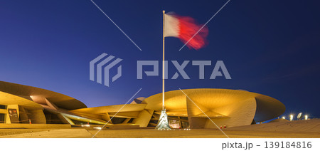 Doha, Qatar - Jan 06 2024, a panoramic view of fluttering Qatar flag in Nation Museum of Qatar, in shape of desert rose, at nighttime with illumination, Doha, Qatar Doha, Qatar - Jan 06 2024, a panoramic view of fluttering Qatar flag in Nation Museum of Qatar, in shape of desert rose, at nighttime with illumination, Doha, Qatar 139184816
