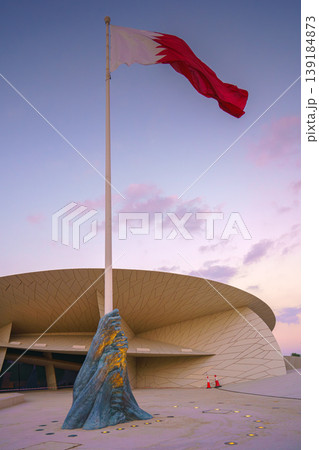 Doha, Qatar - Jan 06 2024, a view of flagpole with the flag of Qatar, fluttering in the wind, with the National Museum of Qatar on background, at evening with cloudy sky, Doha, Qatar 139184873