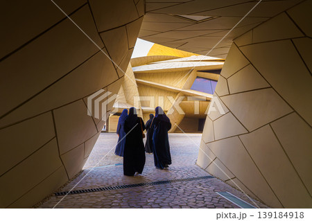 Doha, Qatar - Jan 06 2024, National Museum of Qatar, a view of narrow passage in courtyard with three Arabian woman walking in it, at evening, Doha, Qatar Doha, Qatar - Jan 06 2024, National Museum of Qatar, a view of narrow passage in courtyard with three Arabian woman walking in it, at evening, Doha, Qatar 139184918