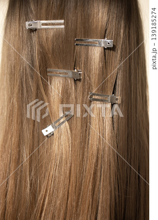 Long, straight blond  hair with silver hair clips arranged neatly, showcasing hair styling accessories against a neutral background for beauty and fashion themes 139185274