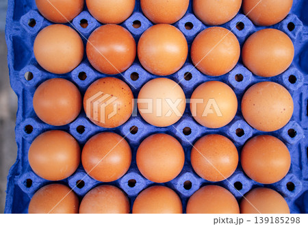 Fresh brown eggs arranged neatly in a blue carton, showcasing various shades and textures, emphasizing natural food presentation and organic farming practices Fresh brown eggs arranged neatly in a blue carton, showcasing various shades and textures, emphasizing natural food presentation and organic farming practices 139185298