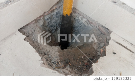 Industrial Hole in Concrete Floor with Yellow Support Pillar 139185323