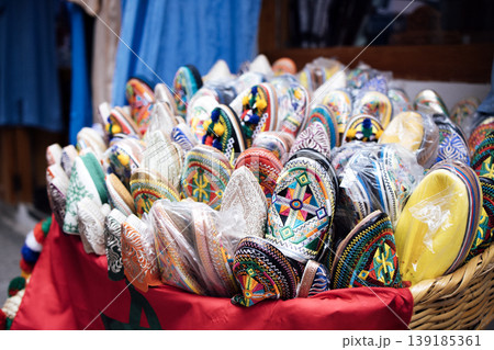 Colorful traditional Moroccan Babouche slippers displayed in a woven basket, showcasing intricate designs and vibrant colors in a market setting 139185361