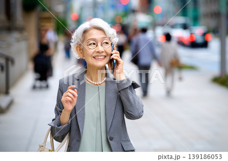 笑顔でスマートフォン通話するアクティブなシニア女性の都市生活 笑顔でスマートフォン通話するアクティブなシニア女性の都市生活 139186053