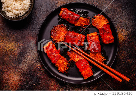 Bacon roll with enoki mushroom grilled with sauce. 139186416