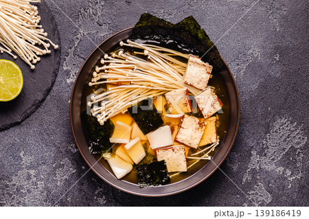 Asian-style soup with squid, tofu and enoki mushrooms. 139186419