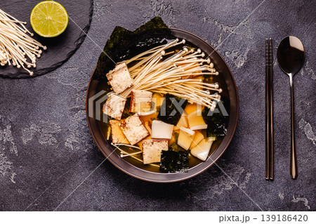 Asian-style soup with squid, tofu and enoki mushrooms. 139186420