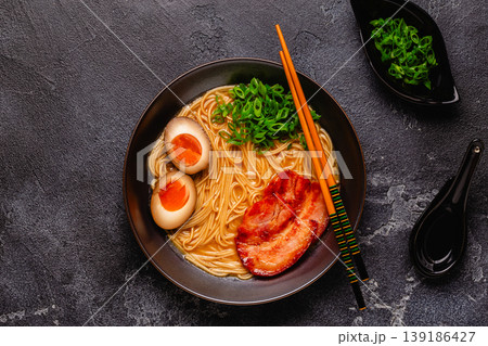 A bowl of ramen with noodles, meat and green onions. 139186427