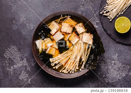 Asian-style soup with squid, tofu and enoki mushrooms. 139186638