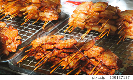 Grilled skewered pork on metal cooling rack at a Thai street food market Grilled skewered pork on metal cooling rack at a Thai street food market 139187157