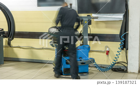 Professional car mechanic replace tire on wheel in auto repair service timelapse. 139187321