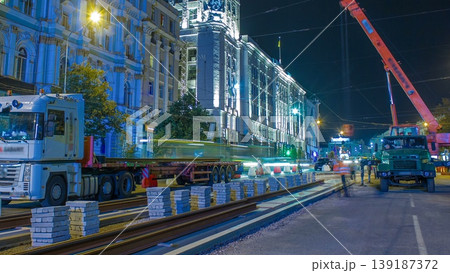Orange construction telescopic mobile crane unloading tram rails from truck night timelapse. Orange construction telescopic mobile crane unloading tram rails from truck night timelapse. 139187372