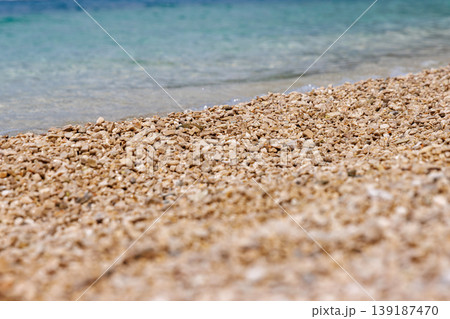 Close up of pebble beach texture with clear turquoise sea water. Shallow depth of field and copy space. Close up of pebble beach texture with clear turquoise sea water. Shallow depth of field and copy space. 139187470