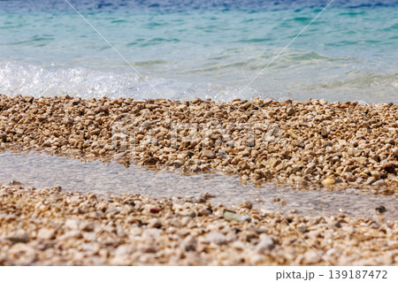 Close up of pebble beach texture with clear turquoise sea water. Shallow depth of field and copy space. Close up of pebble beach texture with clear turquoise sea water. Shallow depth of field and copy space. 139187472