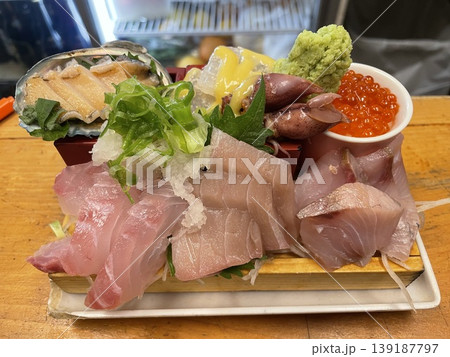 まな板の上で溢れそうに並べられた新鮮な魚や魚介の刺身 まな板の上で溢れそうに並べられた新鮮な魚や魚介の刺身 139187797