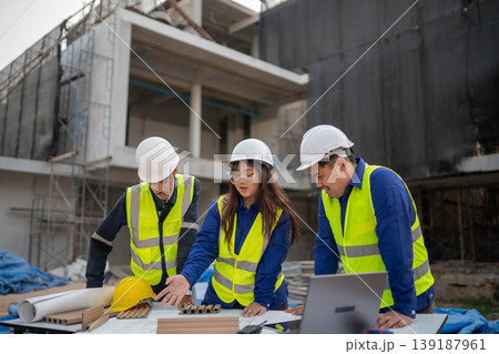 Construction team collaborates on project plans urban building site photo daylight close-up teamwork and planning Construction team collaborates on project plans urban building site photo daylight close-up teamwork and planning 139187961