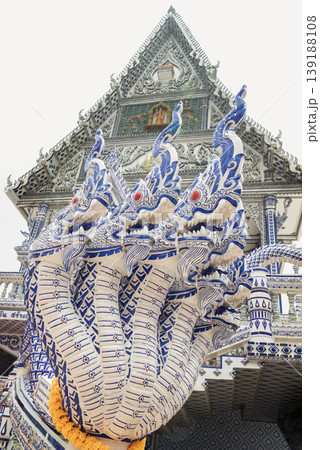 Guarding the entrance of Wat Pak Nam Khaem Nu, the "Blue Temple" with formidable grace, a multi-headed Naga serpent rises in a fan of porcelain power, its scales rendered in the temple's signature 139188108