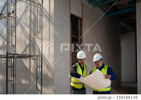 Construction workers analyzing blueprints building site professional collaboration indoor environment focused perspective project planning 139188138