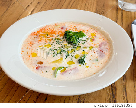 Creamy vegetable fish soup with broccoli, potato pieces and oil drops served in white plate on wooden table. Healthy eating, comfort food, lunch meal and homemade cooking concept. Creamy vegetable fish soup with broccoli, potato pieces and oil drops served in white plate on wooden table. Healthy eating, comfort food, lunch meal and homemade cooking concept. 139188359