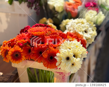 Orange, red and cream gerbera daisy bouquets arranged in a crate at a flower stall. Floral retail, spring color, cut flower display, market abundance, bouquet choice and festive decoration. Orange, red and cream gerbera daisy bouquets arranged in a crate at a flower stall. Floral retail, spring color, cut flower display, market abundance, bouquet choice and festive decoration. 139188425