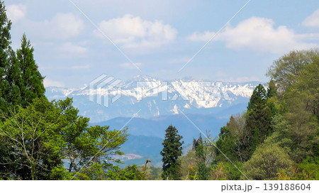 残雪の北アルプスと新緑の森が広がる春の山岳風景 139188604