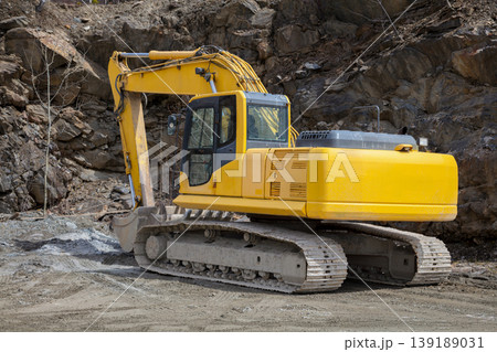 Yellow hydraulic excavator working at rocky quarry construction site 139189031