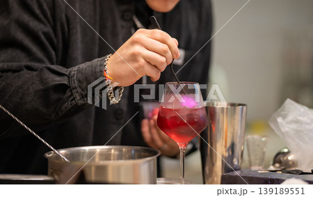 Close-up of a professional bartender stirring a red cocktail Close-up of a professional bartender stirring a red cocktail 139189551